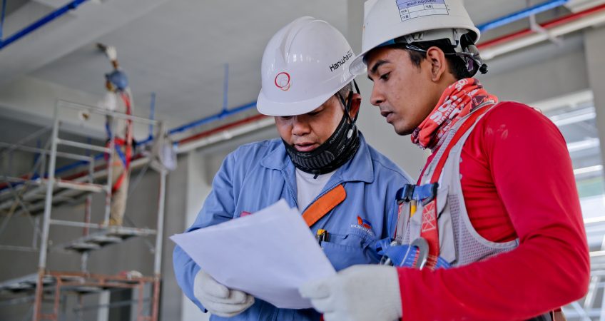 Dos trabajadores de la construcción consultando un plan de seguridad y salud